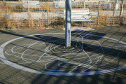 Large-scale steel tetherball with painted line drawing of ball movement on the ground.