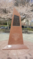 Bust (life size) recessed in pyramidal monument, two plaques with reliefs