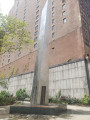 Tall obelisk with variegated surface on a pentagonal base; plaque