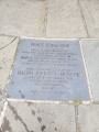 Tall obelisk with variegated surface on a pentagonal base; plaque