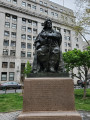 Seated figure (over life-size) with integral plinth, on pedestal