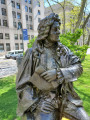 Seated figure (over life-size) with integral plinth, on pedestal