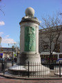 Column topped by a globe, on a circular base; column faced with three bas-reliefs; honor roll of names carved in spaces between the bas-reliefs