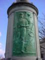 Column topped by a globe, on a circular base; column faced with three bas-reliefs; honor roll of names carved in spaces between the bas-reliefs