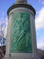 Column topped by a globe, on a circular base; column faced with three bas-reliefs; honor roll of names carved in spaces between the bas-reliefs