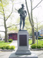 Standing figure (life size), on pedestal with four plaques