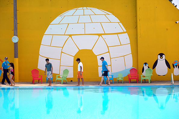 Kids and their families walk by a wall decal of an igloo and penguins at Fisher Pool.