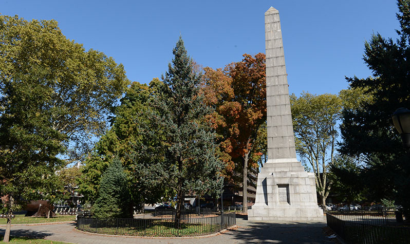 A 75-foot tall obelisk constructed from large blocks of granite surrounded by large trees in a park setting.