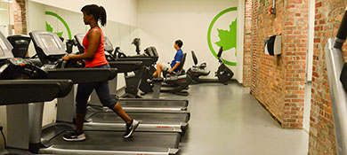 A woman uses a treadmill and a man uses a bike at a rec center.