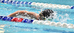 a boy swims in a pool for the swim team