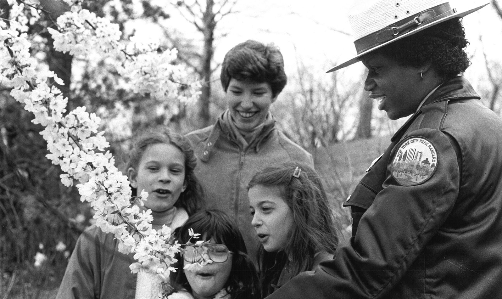 Urban Park Ranger Jackie Brown shows young park goers a flowering cherry tree.