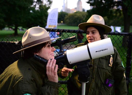 A park ranger looks through a telescope to look to the stars