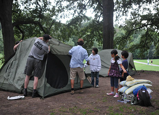 A park ranger helps a family set up a tent in the park