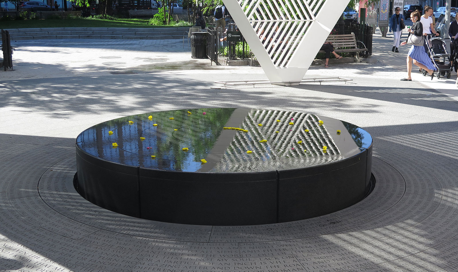 The AIDS Memorial features a white triangular steel sculpture, a central fountain, and benches