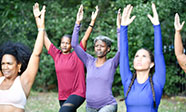 a group of women practice yoga poses in a park