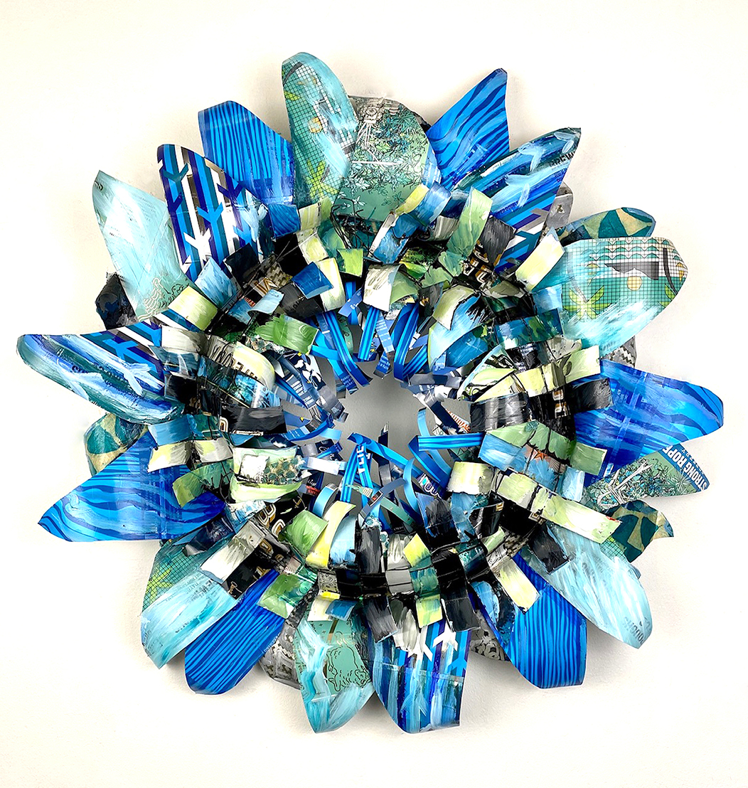 Blue and green beer cans are stripped and arrange into a wreath that looks like one big flower