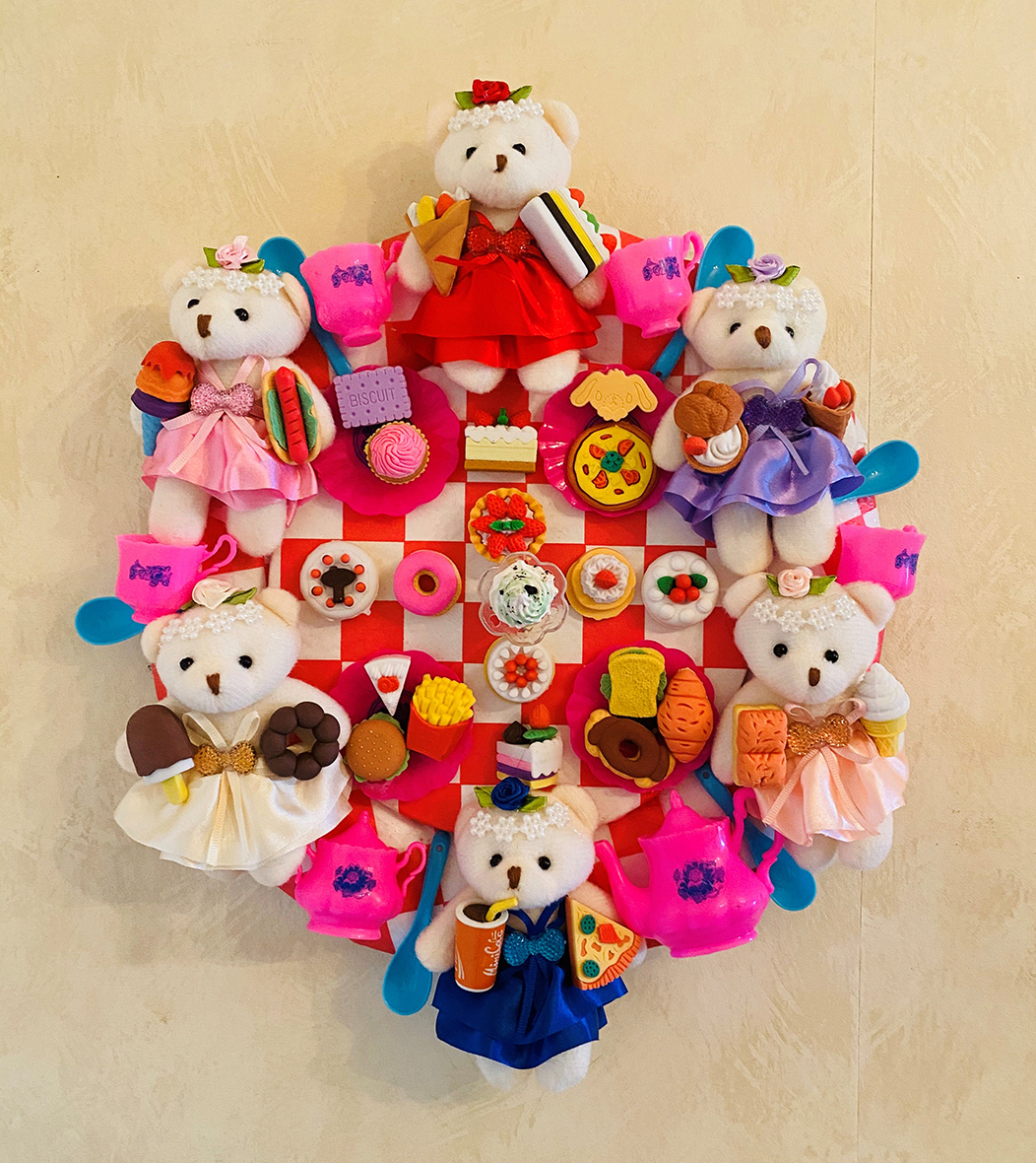 Tiny teddy bears in dresses of various colors and little pink teacups and a teapot are arranged around a wheel of colorful foods, including donuts, pizza, fries, burgers, biscuit and cupcakes