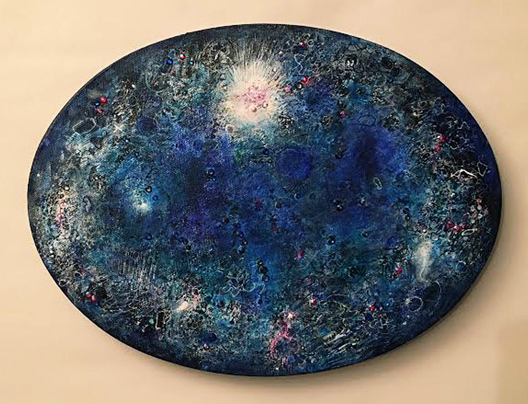 Rhinestones and splashes of color in green, blue, and white are painted on an oval board