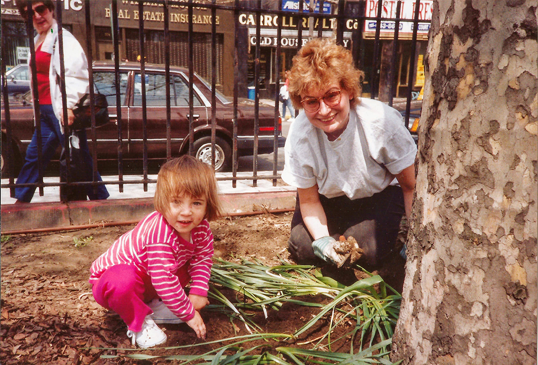 A woman and a kid mulch a tree in the park