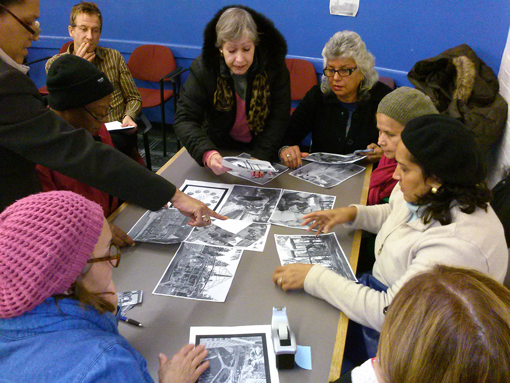 Community members gather at a table to look at printed out black and white images of their park