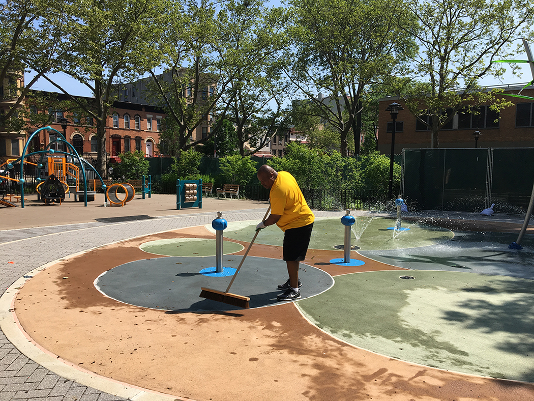 A community member cleans the spray shower area in the playground