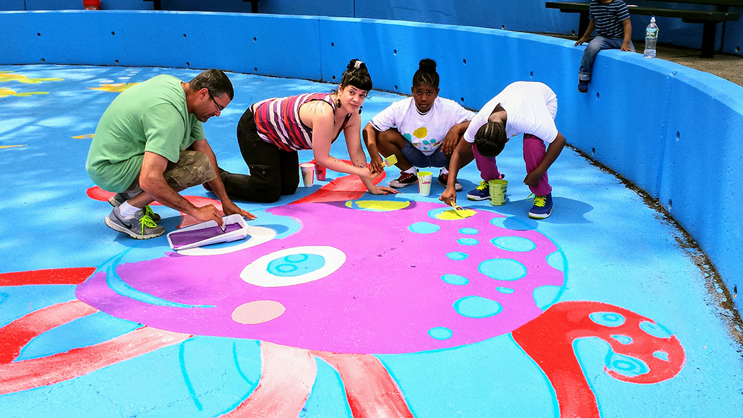 Kids and community members join an artist to paint a mural