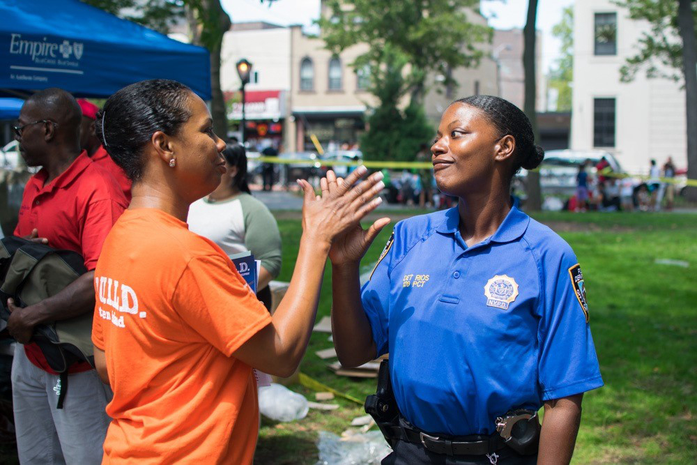 A member of the NYPD Community Affairs unit high fives with a park leader