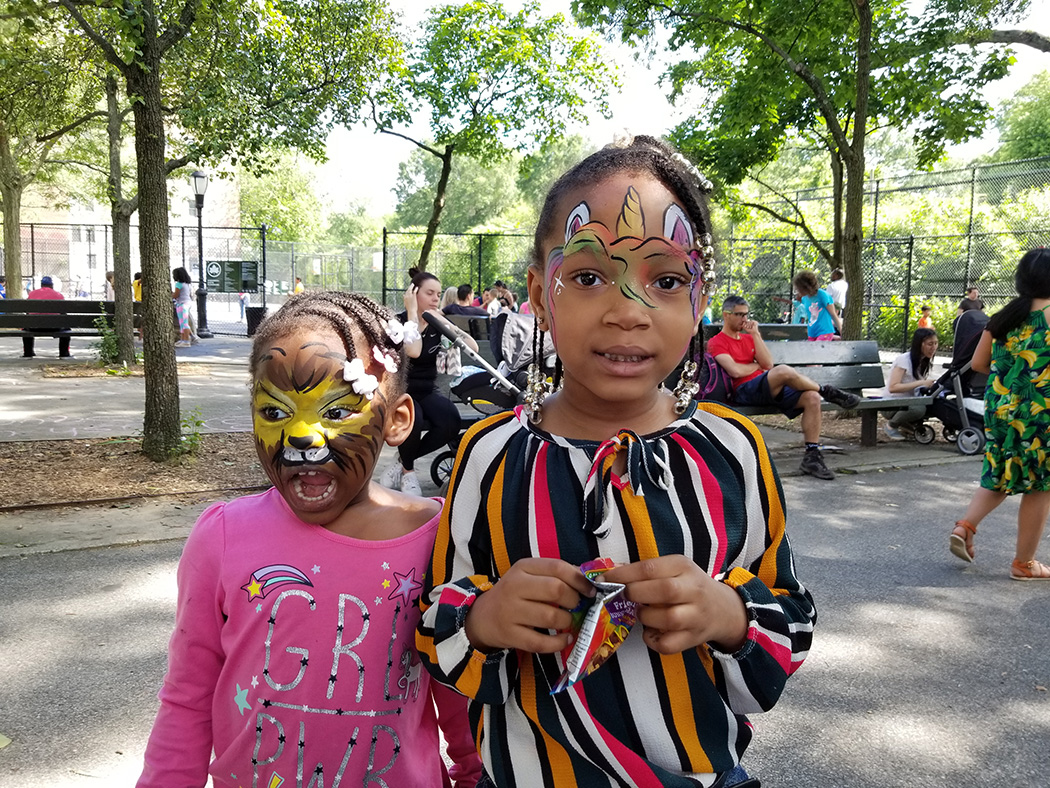 Kids with painted on unicorn and big cat faces pose for a photo