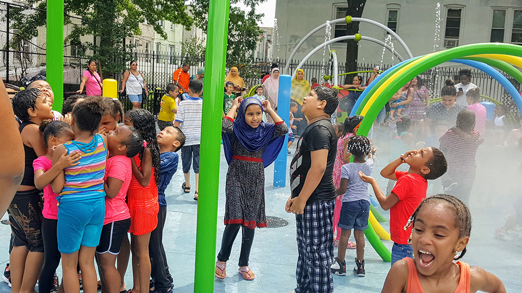 Kids enjoy getting splashed with water at the spray showers in the park