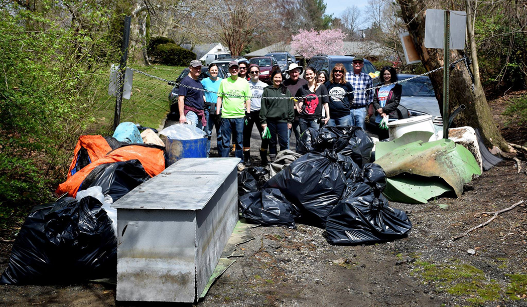 Community members pose next to bags of trash picked up