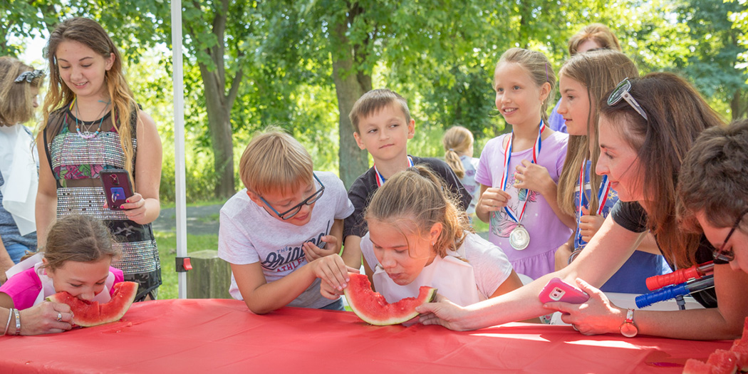 Kids gather around the table to watch the watermelon eating contest