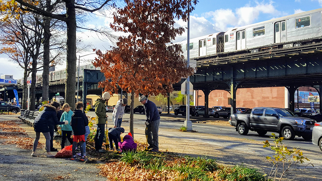 Kids and other community members care for a tree along a park path next to the subway station