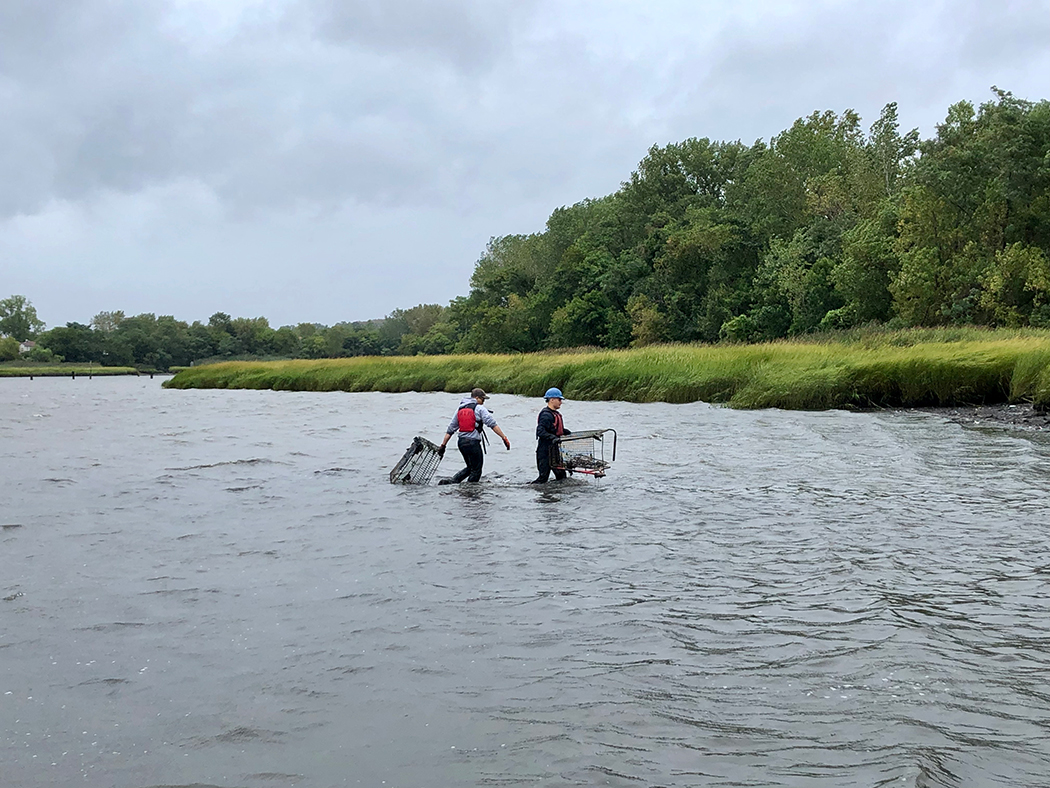 Two people carry out shopping carts from the water