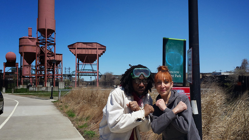 Community members make an X with their arms while posing next to the old concrete plant