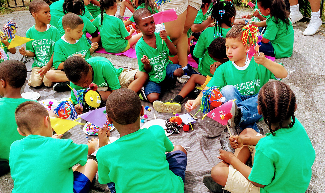 Kids of the Police Athletic League enjoy crafts while sitting in the park