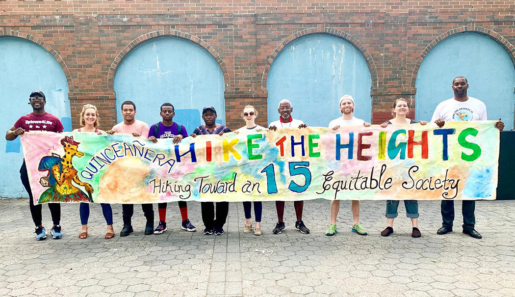 Community members hold up a sign that reads quinceanera, hike the heights 15, hiking toward an equitable society