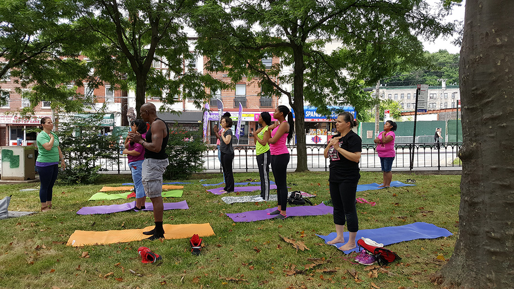 Community members take off their shoes and stop on mats on the lawn to work out