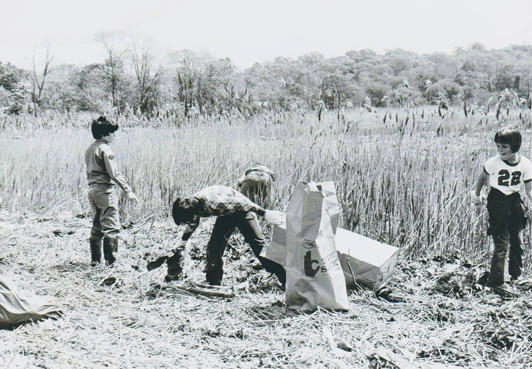 black and white archival image of kids picking up debris at a marsh