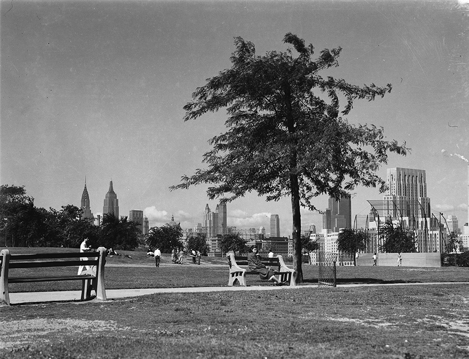 black and white archival image of folks enjoying the day out in the park which features a view of the Manhattan skyline