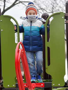 a kid plays on the play equipment