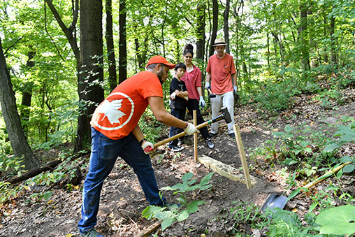 a Parks worker and volunteers help create steps on a trail