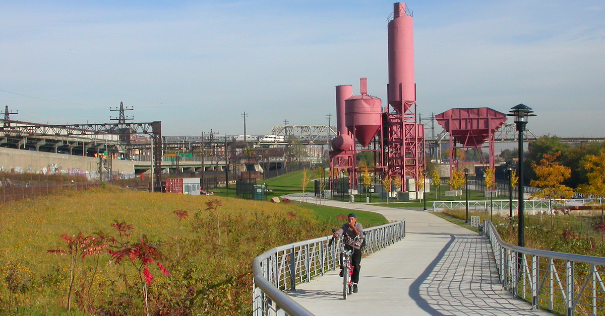 a cyclist rides through Concrete Plant Park with features remnants of an old factory near a river