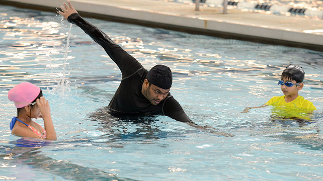 an instructor shows kids how to swim