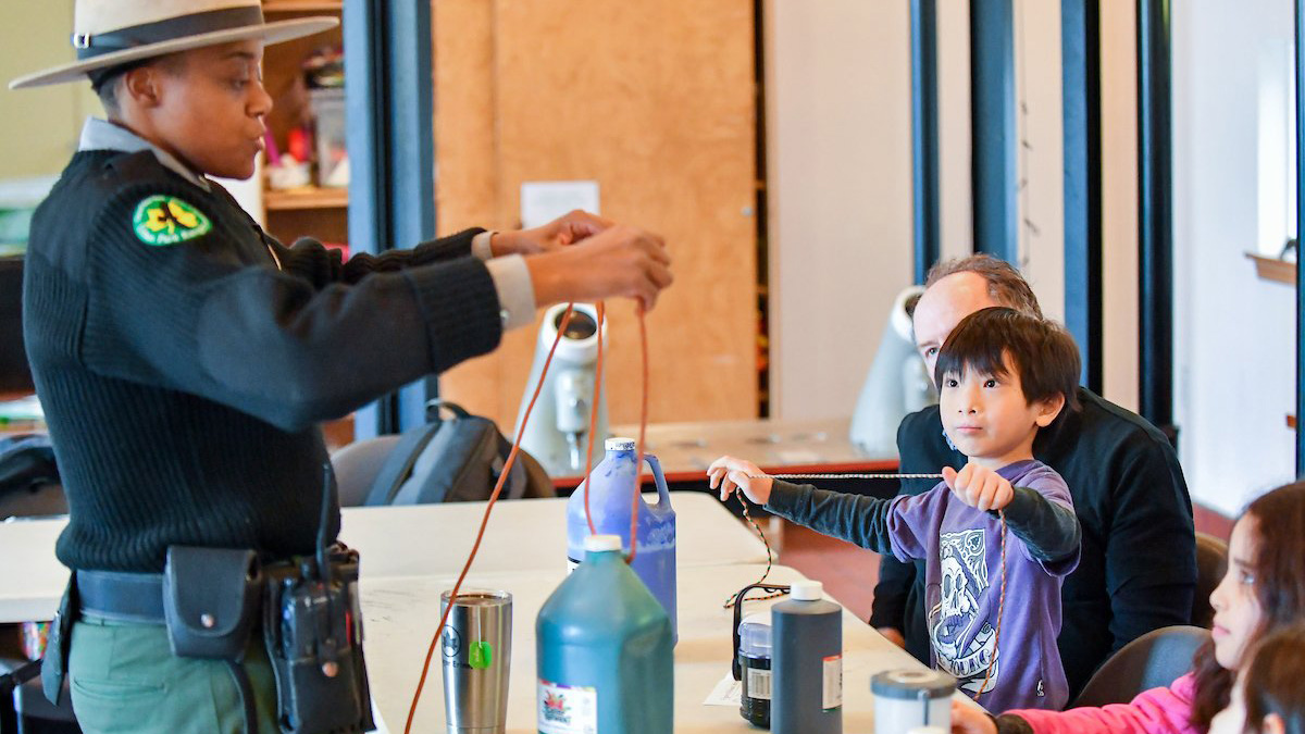 a park ranger demonstrates to kids how to make knots