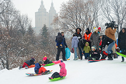 Kids and their families enjoy sledding down the hill in Central Park