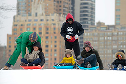 Parks staff assists kids and their families in getting ready to sled down the hill