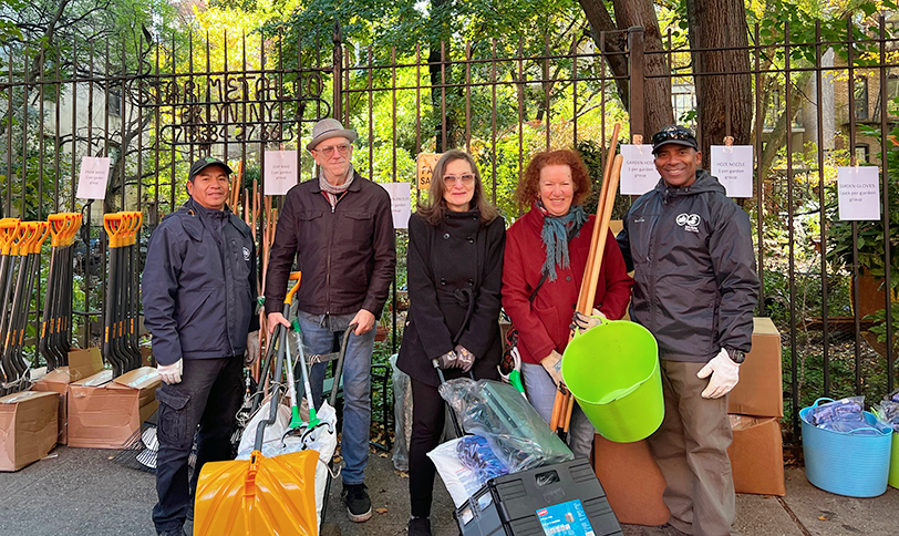 attendees at community garden resources event pose with community gardeners in front of gardening tools.