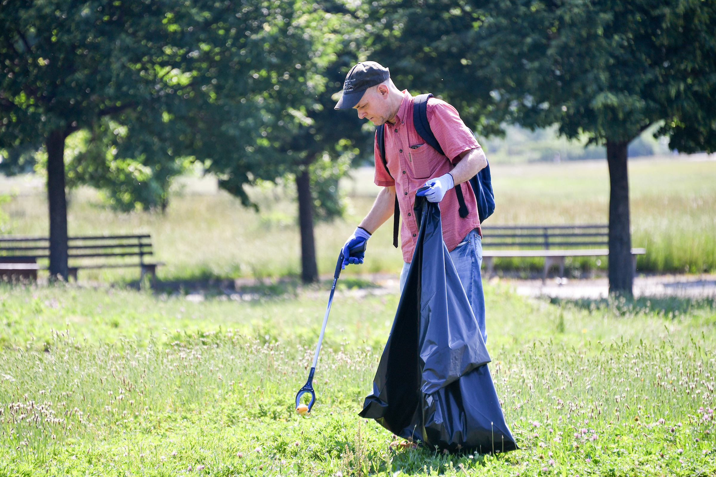 a volunteer pick up trash on the parks lawn