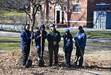 NYC Parks uniformed workers pose with outdoor cleaning equipment.