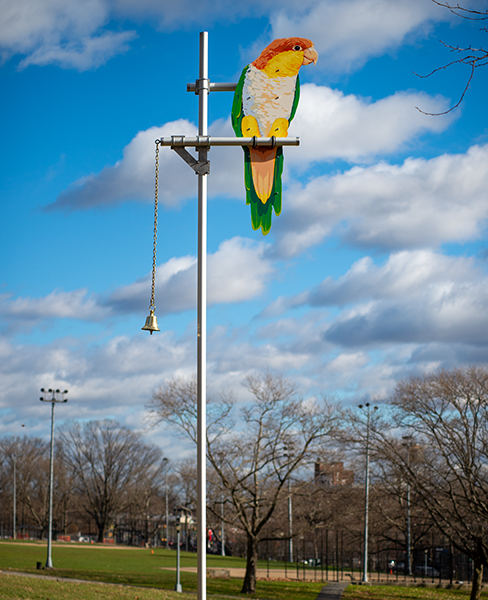 Big Bird features a six-foot-tall aluminum cutout of a white-bellied caique parrot, hand-painted in sign enamel. The bird is perched twenty feet above the ground, as if it were surveying the activities of park-goers below. Hanging from the perch is a bronze bell, recalling the types of 